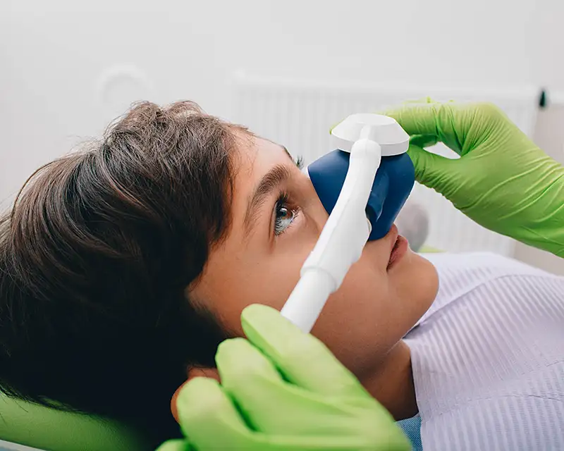 Patient receiving dental examination with dental mirror and tool in clinical setting.